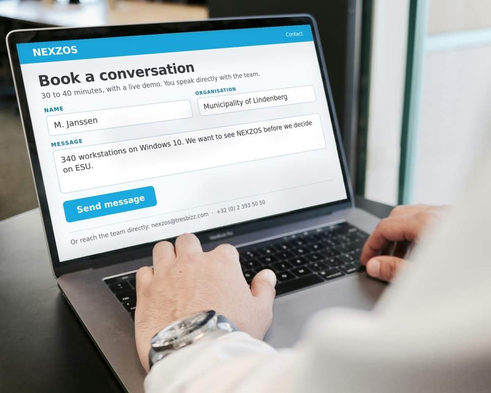 Handen op een laptoptoetsenbord, het NEXZOS-contactformulier ingevuld op het scherm