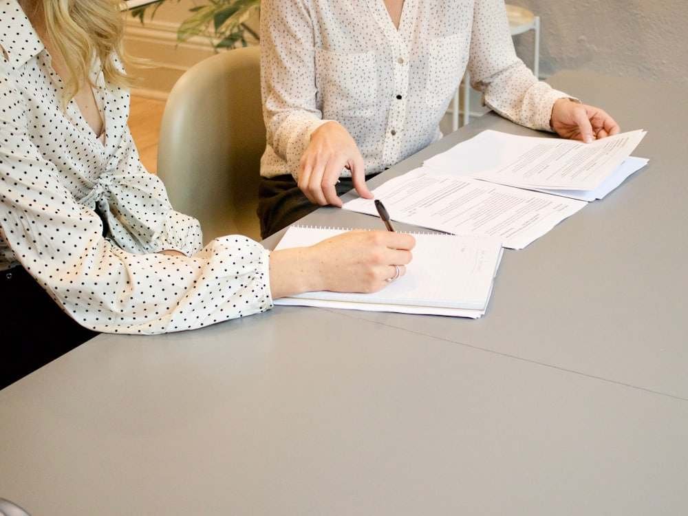 Twee mensen die een document doornemen aan een bureau, één ondertekent