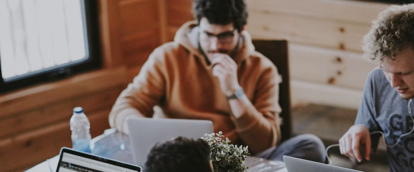 Drie collega's die samen aan één werktafel met laptops werken