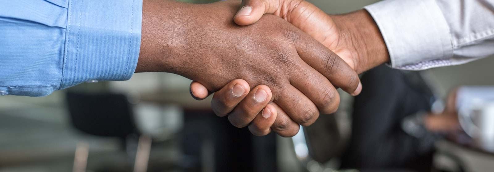 Ein Handschlag über einen Besprechungstisch hinweg